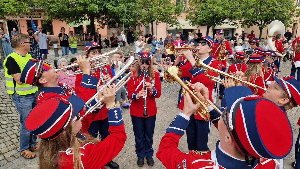 Trobonister i uniform fra Kjelsås skoles musikkorps står i ring rundt klarinettist. 